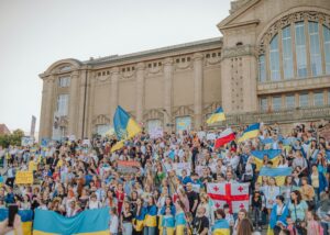 A vibrant crowd gathers in Szczecin, Poland for a public demonstration waving various national flags.