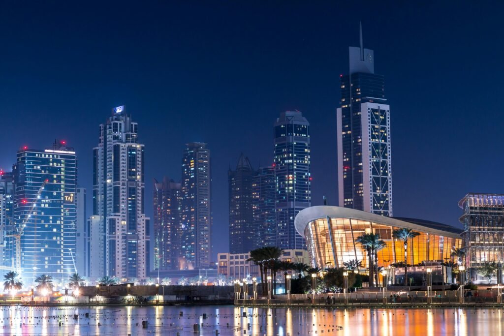 Stunning view of Dubai's illuminated skyline with modern skyscrapers reflecting on water at night.