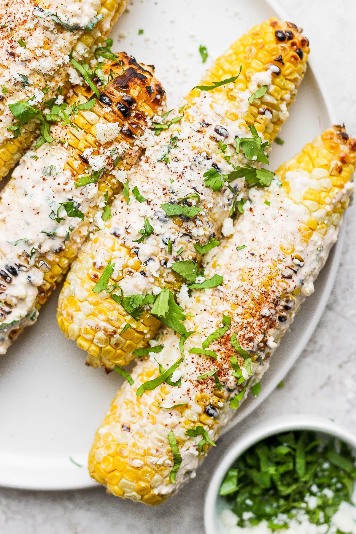 mexican street corn on a white plate topped with cilantro and cotija